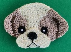 a crocheted dog head on a green surface