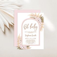 a pink and gold baby shower with flowers on the front is next to a palm leaf