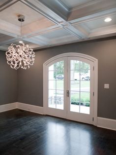 an empty room with two doors and a chandelier hanging from it's ceiling