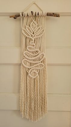 a white wall hanging on the side of a door with ropes and beads attached to it