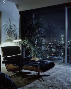 a living room filled with furniture and a large window overlooking the city lights at night