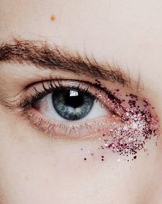 a woman's eye with pink glitter on the top of her lashes and under her eyes