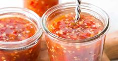 two jars filled with food sitting on top of a wooden cutting board