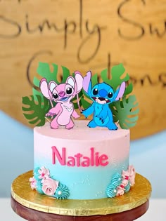 there is a pink and blue cake with two little cartoon characters on it that says natalie