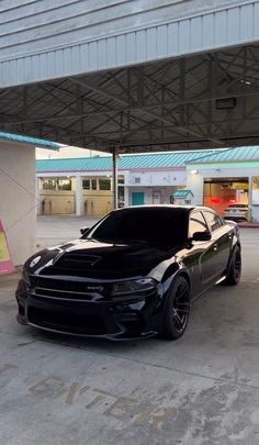 a black car parked in front of a gas station