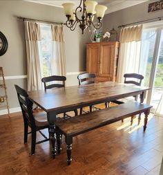 a dining room table with two benches in front of it and a clock on the wall