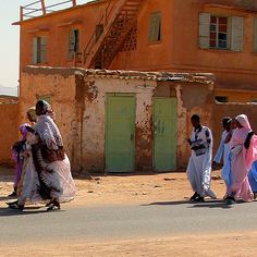 four people walking down the street in front of an old building