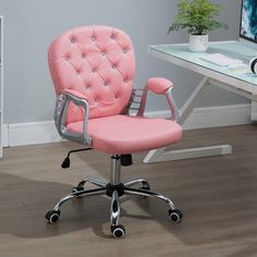 a pink office chair sitting on top of a wooden floor next to a computer desk