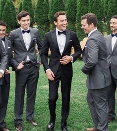 a group of men standing next to each other wearing suits and bow ties on the grass