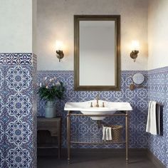 a bathroom with blue and white tiles on the walls, sink and mirror in it