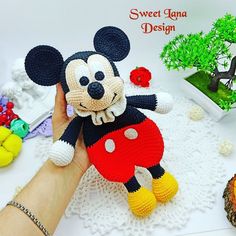 a hand holding a crocheted mickey mouse