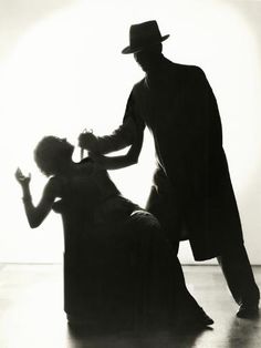 an old photo of a man dancing with a woman sitting on the floor in front of him