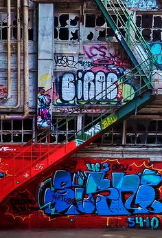 graffiti is painted on the side of an old building with stairs leading up to it