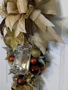 a christmas wreath on the front door decorated with gold and silver ornaments, ribbons and lights