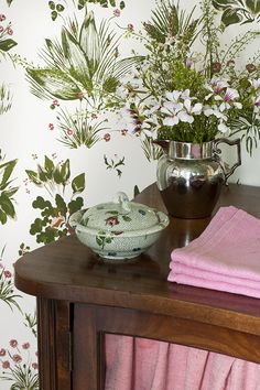 a table topped with a bowl of flowers next to a vase filled with white flowers