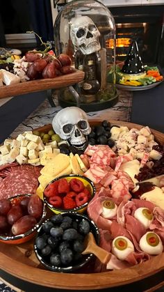 a wooden platter filled with meats, cheeses and fruit on top of a table