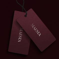 two red tags with the word alaska on them hanging from a rope against a dark background