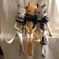 three cats sitting on top of each other in front of a white curtain with blue eyes