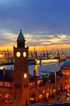 Clock tower and harbor with cranes at sunset, creating a picturesque skyline.