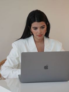 a woman sitting at a table with an apple laptop in front of her on her