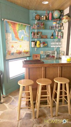 three stools in front of a bar with a map on the wall