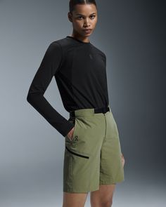 a woman in black shirt and khaki shorts standing with her hands on her hips