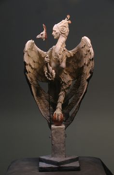 a statue of an angel holding a flag on top of a wooden block in front of a dark background