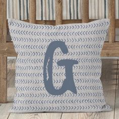 a pillow with the letter g on it sitting in front of a wooden rocking chair