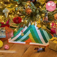 a christmas tree with presents under it on the floor and an ornament in front of it