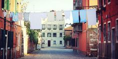 an alley way with clothes hanging out to dry in front of the buildings on either side