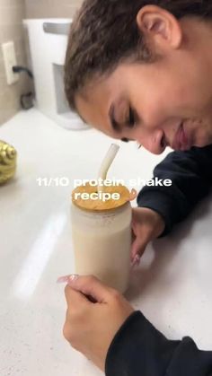 a man holding a cup with a straw in it while looking down at the ground