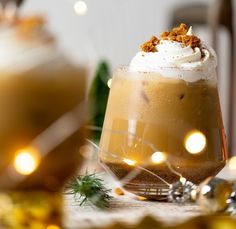 two glasses filled with drinks sitting on top of a table next to christmas decorations and lights