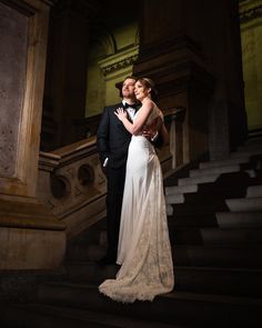 a bride and groom standing on the stairs at night