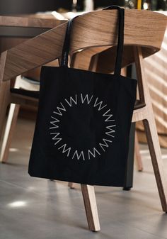 a black tote bag sitting on top of a wooden chair next to a table