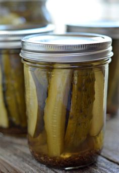 pickles in jars sitting on a wooden table