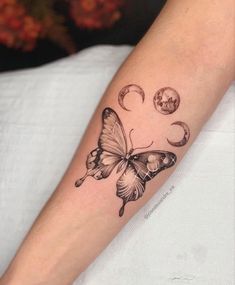 a butterfly tattoo on the arm with phases and stars around it, as well as crescents