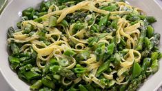 a white bowl filled with pasta and asparagus