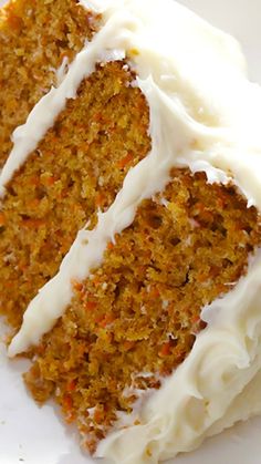 a slice of carrot cake with white frosting on a plate next to a fork