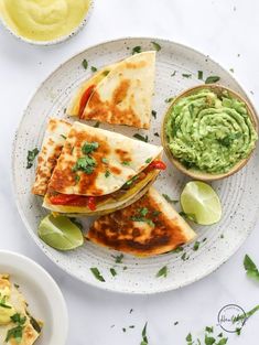 three quesadillas on a plate with guacamole and salsa