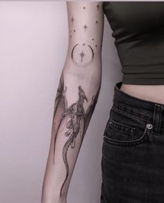 a woman's arm with a lizard on it and stars in the sky behind her