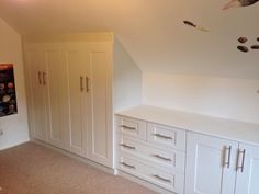 a room with white cupboards and drawers in the middle of an area that has carpeted flooring