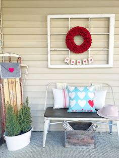 a white bench sitting next to a red wreath on top of a window sill