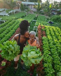 two women standing in a garden with lots of lettuce