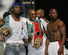 four men standing next to each other holding up their boxing belts and posing for the camera