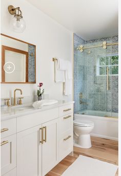 a bathroom with blue and white tiles on the walls, wood flooring and gold fixtures