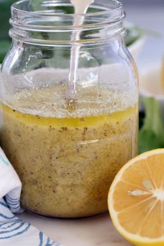 a glass jar filled with liquid next to sliced lemons