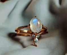 a gold ring with an opal and diamond accented band on top of a white fabric