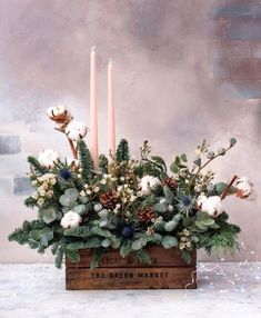 a wooden box filled with flowers and candles on top of a white tablecloth covered floor