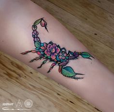 a woman's leg with flowers and leaves tattooed on the side of her arm