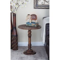 an elephant figurine sitting on top of a table next to a vase with flowers